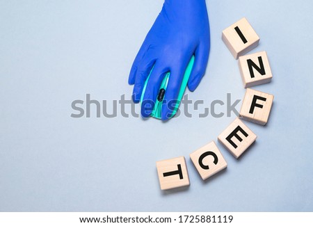the word infect is from wooden cubes on blue grey background with computer mouse and hand in medical glove