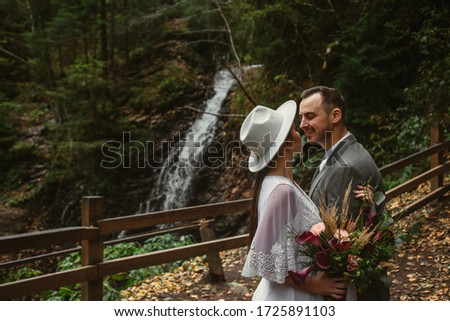 The bride and groom in the mountains against the backdrop of a waterfall in the forest. mountain wedding. forest wedding. wedding photo shoot. Ukrainian Carpathians