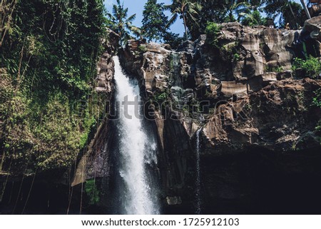 Photo of a large waterfall in rocks with palm trees