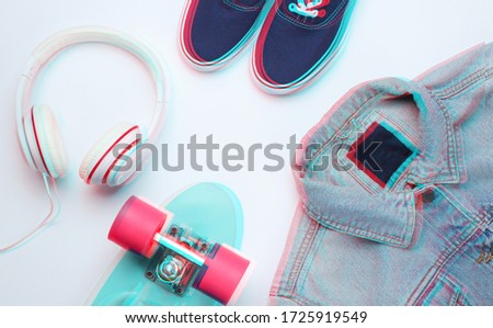 Hipster fashion look. Denim jacket, skate, sneakers, headphones on a white background. Glitch effect. Top view. Flat lay