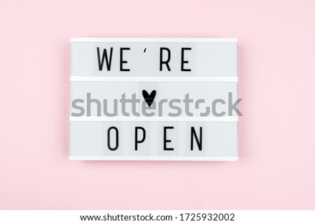 lightbox with the words WE are OPEN on a pink background. Starting a business after the pandemic.