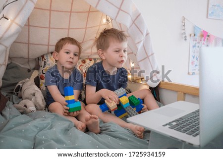Toddler boys sitting on bed with laptop. Watching cartoons, video chatting, distance education. lockdown, quarantine. Lifestyle family