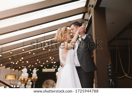 The first wedding dance. Wedding couple bride and groom dancing in a restaurant on a background of light bulbs. Portrait.