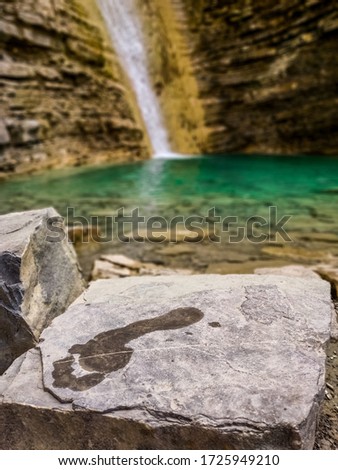 A footprint on the stone behind the waterfall