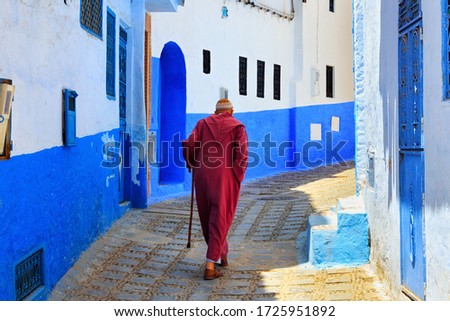 Unknown elderly man in Medina quarter in Chefchaouen, Morocco. The city, also known as Chaouen is noted for its buildings in shades of blue and that makes Chefchaouen very attractive to visitors. Royalty-Free Stock Photo #1725951892