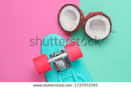 Creative summer concept. Skateboard, coconut halves on blue pink pastel background, top view