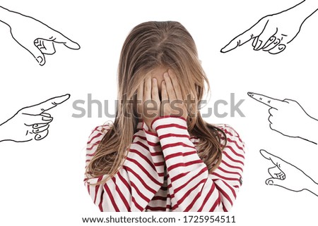 young lonely teenage girl crying on studio isolated white background with drawings of pointing fingers symbolizing harassment