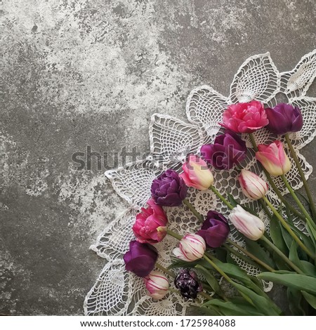 A bouquet of Multi-colored tulips at vintage knitted napkin on a gray concrete background, copy space. 