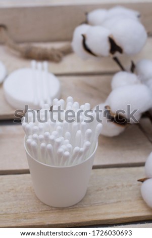 Clean cotton sticks for personal ears hygiene. Cotton buds and discs on wooden tray with cotton branch.