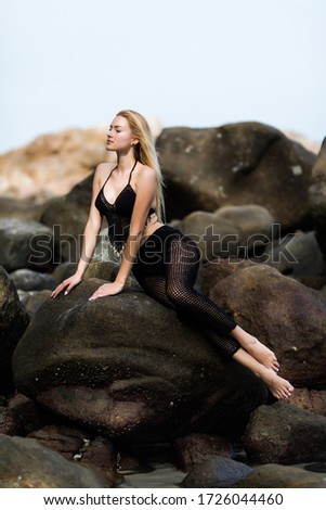 Young woman sitting on the rocks on the beach