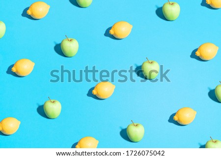 Lemon and apple pattern on bright light blue background. Minimal flat lay food texture. Summer abstract trendy fresh concept.