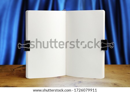 Notebook mockup on a background of wooden table and blue drapery, mock up