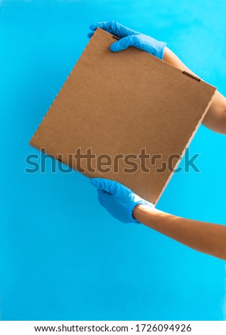 Courier delivery of food in containers. Courier girl holding containers on a blue background. Delivery on self-isolation. A volunteer delivers food. The concept of food delivery. Take-away food.