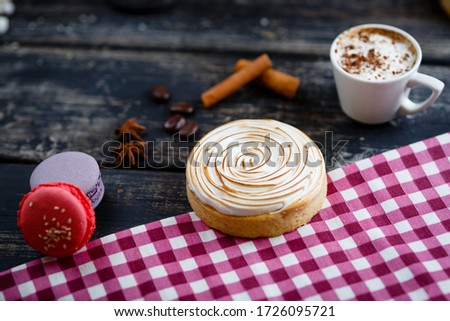 Small handmade pies, cakes, tartlets with lime curd, meringue. Dark wooden board, macaroons on the background. Selective focus