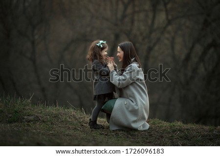Mom and daughter have fun on a walk in the spring forest.
Image with selective focus, noise effects and toning. Focus on the girl and mom.