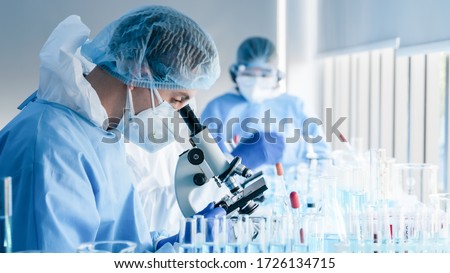 biochemical research scientist team working with microscope for coronavirus vaccine development in pharmaceutical research labolatory, selective focus Royalty-Free Stock Photo #1726134715