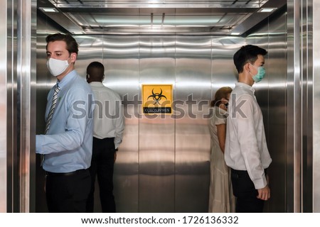 caucasian businessman and people standing apart from each in corner of elevator for social distancing to avoid coronavirus covid-19 spreading with coronavirus alert sign in elevator, selective focus