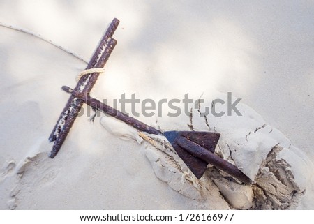 Anchor and white rope on the sand.