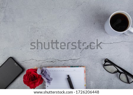 over head top view of office stuff with Cup of coffee, notepad, smartphone and eye glasses