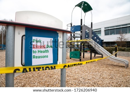 "Park Closed Due to Health Reasons" sign at a playground shutdown with caution tape during the Covid-19 pandemic