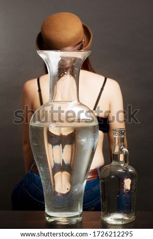 portrait of woman in Studio, in the brown hat and leather gloves Through a water vessel. with Funny Distorted Eyes