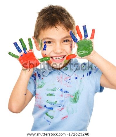Portrait of a cute cheerful boy showing her hands painted in bright colors, isolated over white