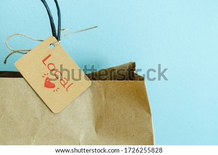 Paper shopping bag with label on blue background. Label with heart and text LOCAL. Shopping concept. Copy space. Royalty-Free Stock Photo #1726255828
