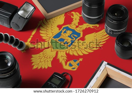Montenegro national flag with top view of personal photographer equipment and tools on white wooden table, copy space.