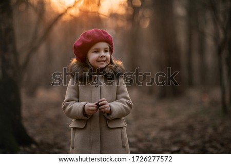 Portrait of a girl in the autumn forest. The girl is dressed in a brown coat and a burgundy beret. Image with selective focus and toning. Image with noise.