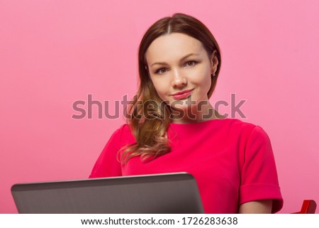 beautiful young woman with laptop on pink background with hand gesture