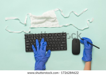 Hands in medical gloves with a pencil and keyboard on a light background. Prevention of the spread of coronavirus.
