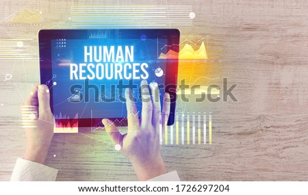 Close-up of hands holding tablet with HUMAN RESOURCES inscription, modern business concept