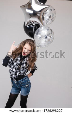 Cool pre-teen girl with rock sign. She is showing rock n roll or horn sign, gesturing at camera and pouting her lips with two air balloons. Stock studio portrait isolate on grey.