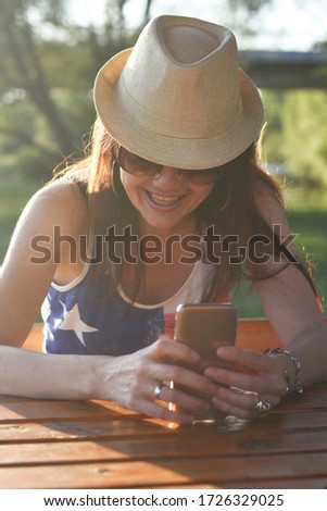 Smiling woman reading message on phone in sunset . Beautiful middle aged woman typing on smart phone