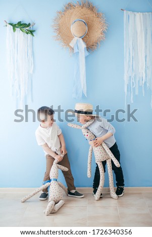 Stock Photo -  Boys play with rabbit indoors in spring. Decorated home and spring flowers. Family celebrating Easter