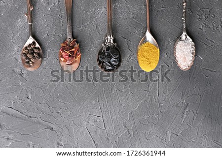 Colourful various spices for cooking in spoons on dark background. curcuma powder, juniper berries, himalayan salt and red pepper to make spycy hot asian meal. vintage spoons. copy space for text