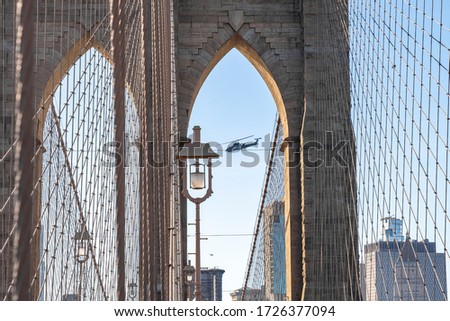 Close up view of the Brooklyn bridge with military choppers flying over it.