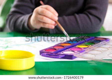Kid painting with watercolor indoors