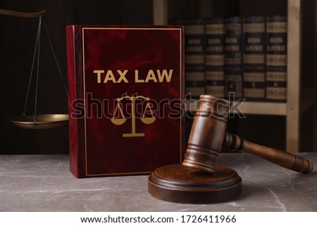 Tax law book and gavel on grey marble table