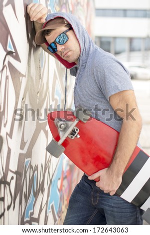 Portrait of pensive and serious skateboarder with skate, outdoor