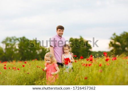 Beautiful little child girl in dress with dad picking flowers in poppy field. 