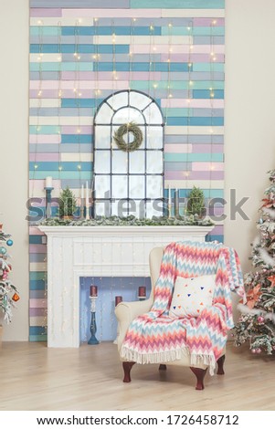 A room with a Christmas decoration in pink blue and white tones. A chair near the fireplace and the Christmas tree. Two Christmas trees in the living room luxury design.