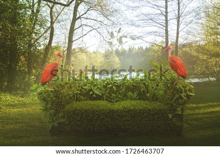 A Surreal Fantasy photo-manipulation with a mossy sofa outside by the lake in the forest and a two flamingos sitting on it. Idyllic scenery as if it came out of a fairy tale.  