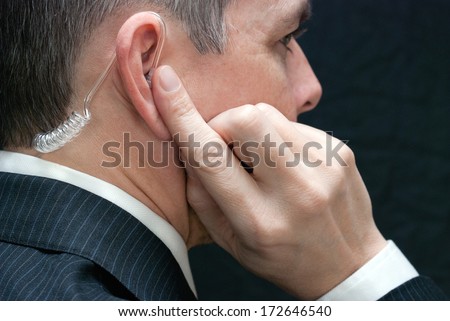Close-up of a secret service agent listening to his earpiece, close side. Royalty-Free Stock Photo #172646540