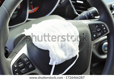 protective medical mask lies on the steering wheel of a car