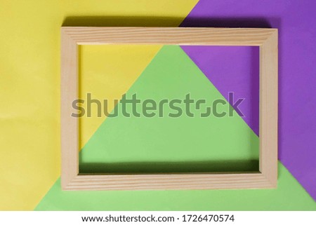 Wooden frame on a colourful background. Yellow, green and purple background. Blank mock up with a wooden frame.