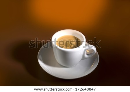 closeup photo of cup of coffe with heart shaped foam in the middle on brown orange background