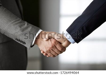Business people in office suits standing and shaking hands, close-up. Business communication concept. Handshake and marketing Royalty-Free Stock Photo #1726494064