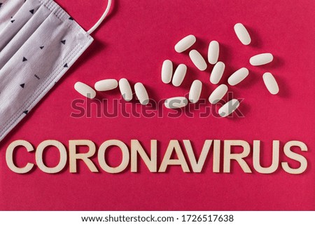 Coronavirus word written with wooden letters and medicine tablets, top view
