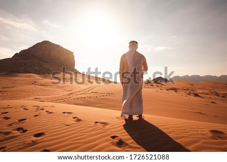 Arab man stands alone in the desert and watching the sunset. Royalty-Free Stock Photo #1726521088